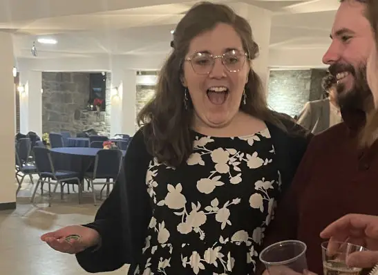 Woman reacting with excitement during a close-up coin magic trick at an event