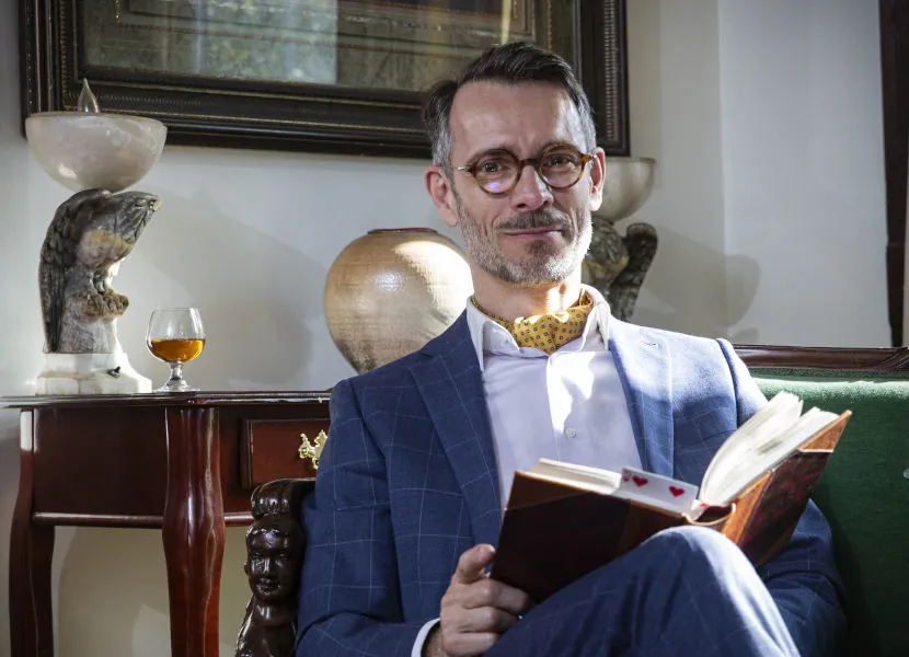 Elegant magician seated and reading a book in a refined setting