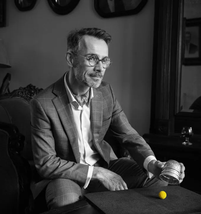 FX holding a cup and ball during a close-up magic performance, black and white portrait