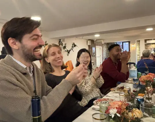 Guests laughing and reacting to a close-up card magic trick during a dinner event