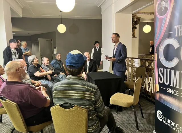 Magician performing a parlor magic show for a live seated audience