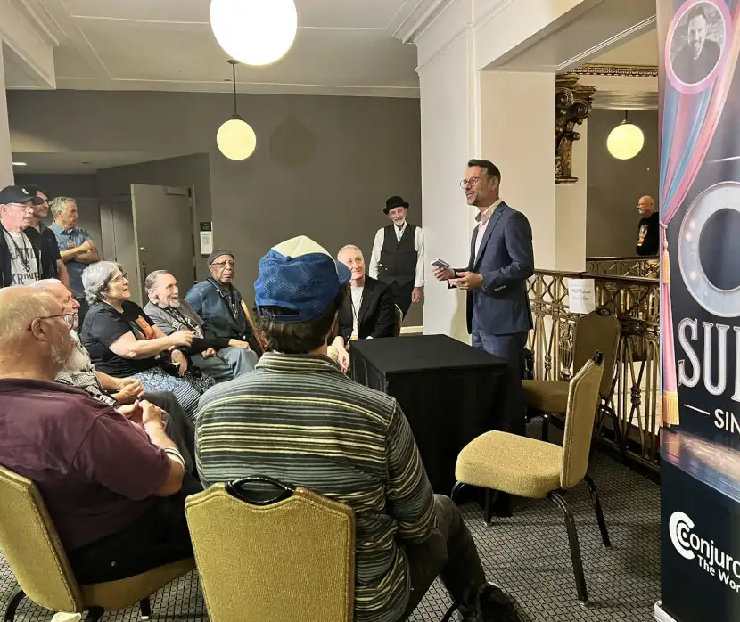 Magician performing a parlor magic show for a seated audience