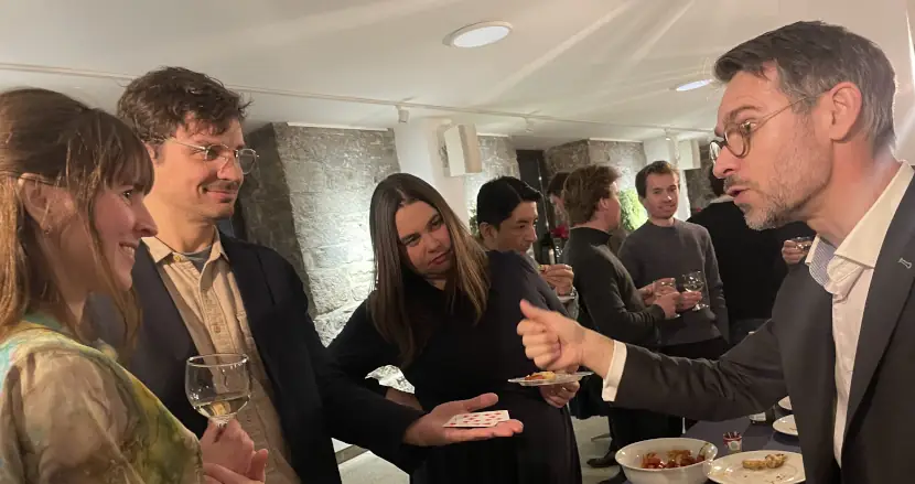Magician performing an interactive close-up magic trick for guests at a private reception