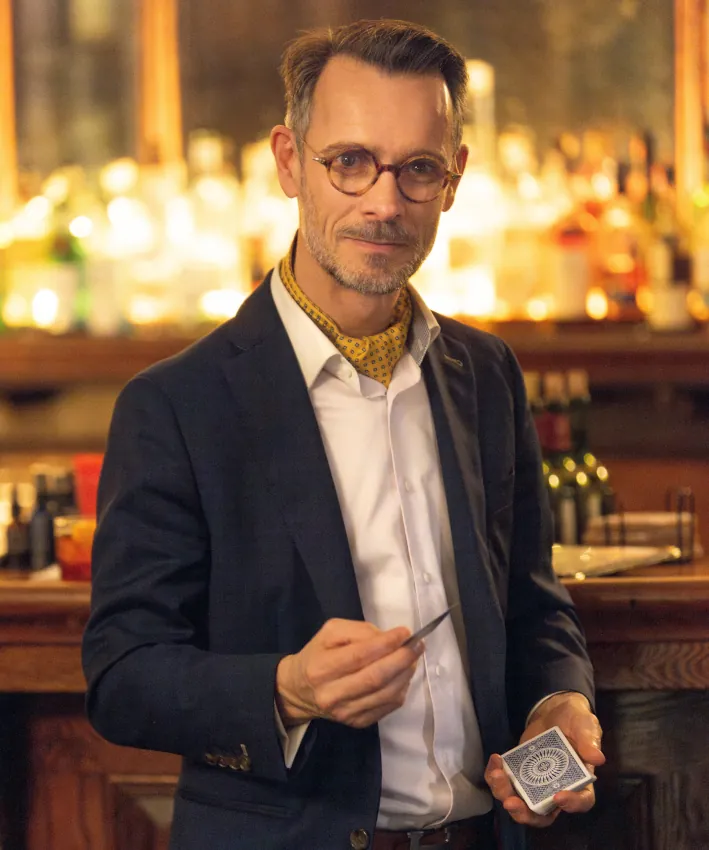 Elegant magician performing a close-up card trick in a bar setting