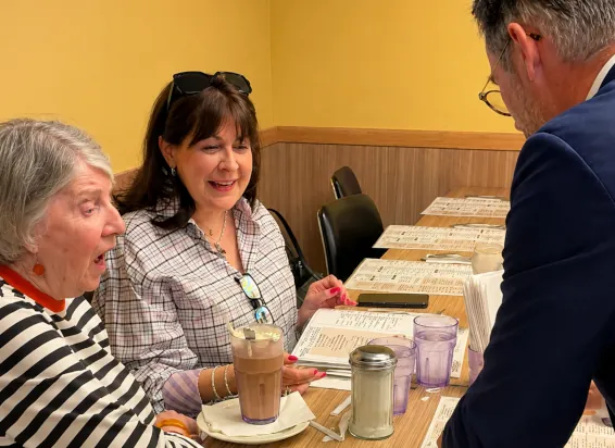 Two guests reacting with surprise and delight during a close-up magic performance at a dining table