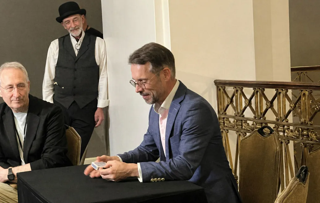 Magician performing close-up card magic at a table in a formal setting