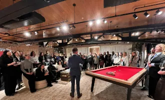 FX performing magic for a large group of guests gathered around a billiard table