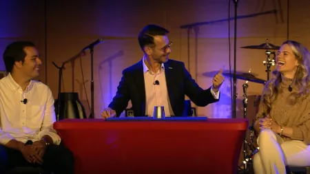 FX performing close-up magic for two seated guests during a live event